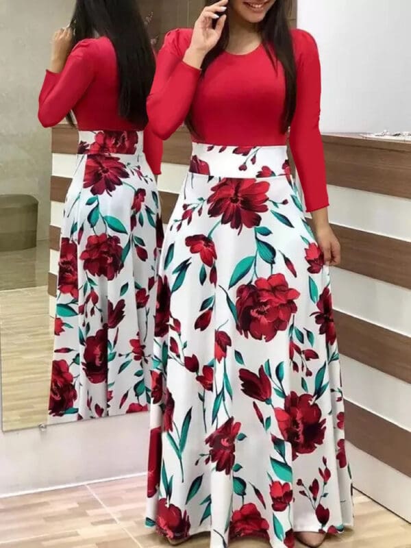 A woman in red top and floral skirt standing next to mirror.