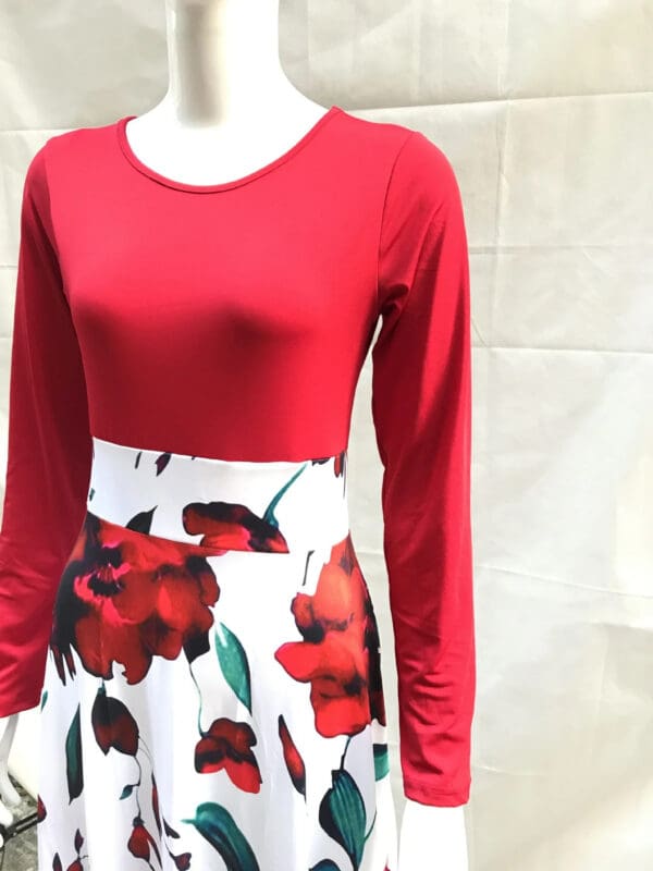 A red top with long sleeves and a floral skirt.