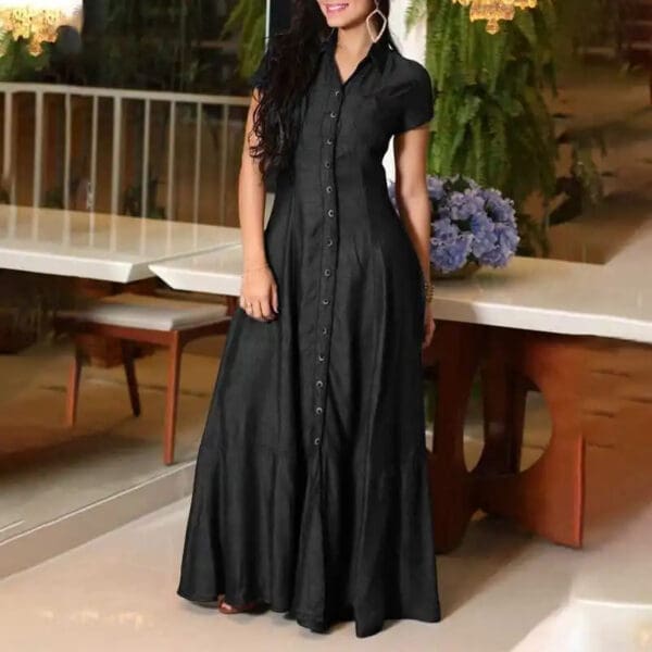 A woman in black dress standing next to a table.