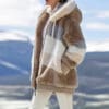 A woman in white pants and a brown jacket