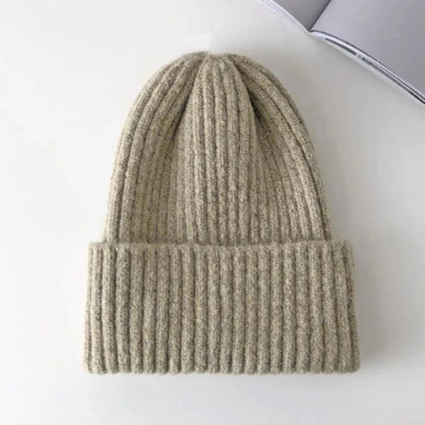 A beige beanie hat is sitting on top of a table.