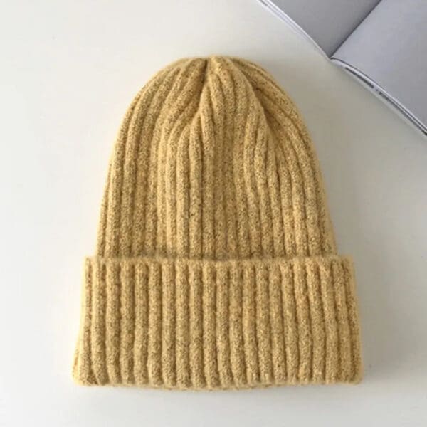 A yellow beanie is sitting on top of a table.