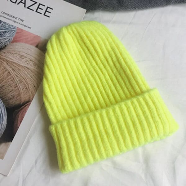 A neon yellow beanie hat sitting on top of a bed.