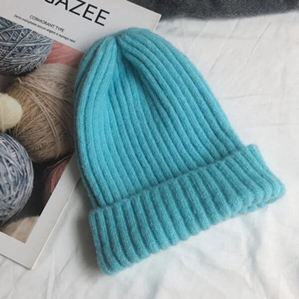 A blue knitted hat sitting on top of a bed.