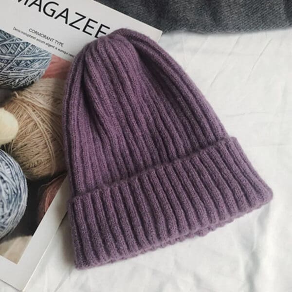 A purple knitted hat sitting on top of a magazine.