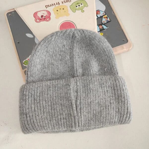 A gray beanie is on top of an open book.