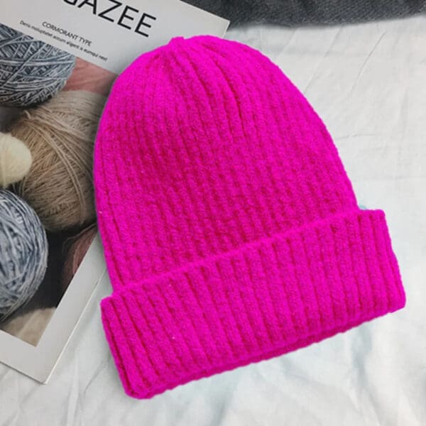 A pink beanie is sitting on top of a table.