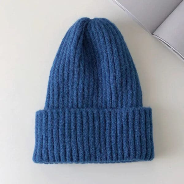 A blue knitted hat on top of a table.