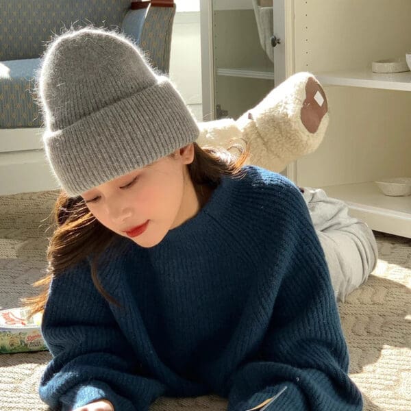 A young girl wearing a hat and sitting on the floor.