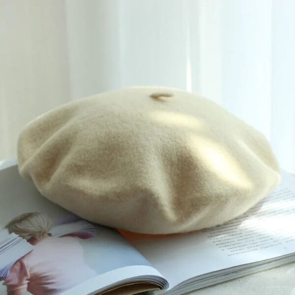 A white beret sitting on top of a book.