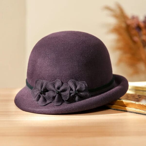 A purple hat with flowers on it sitting on top of a table.