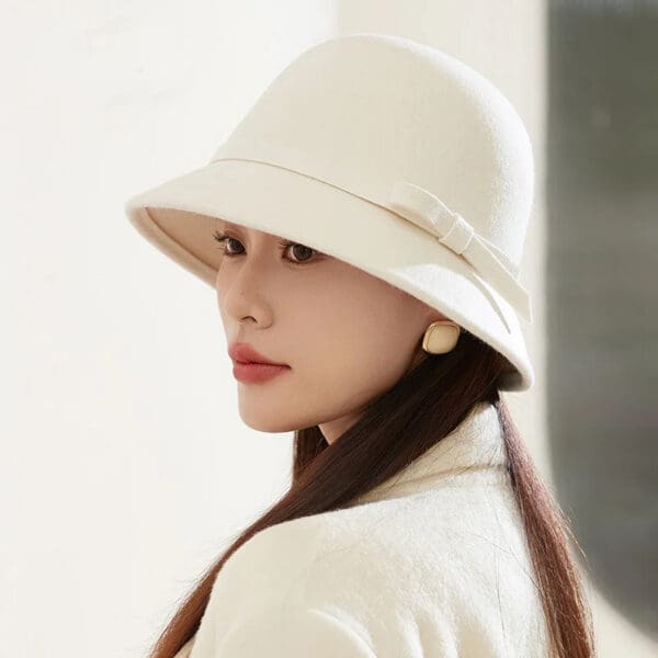 A woman wearing a white hat and holding her head.