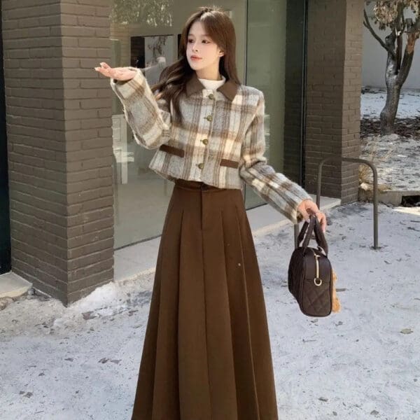 A woman in brown skirt holding a purse and standing on the sidewalk.