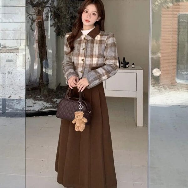 A woman in brown skirt and jacket holding a teddy bear.