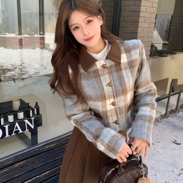 A woman standing on the sidewalk holding onto a brown purse.