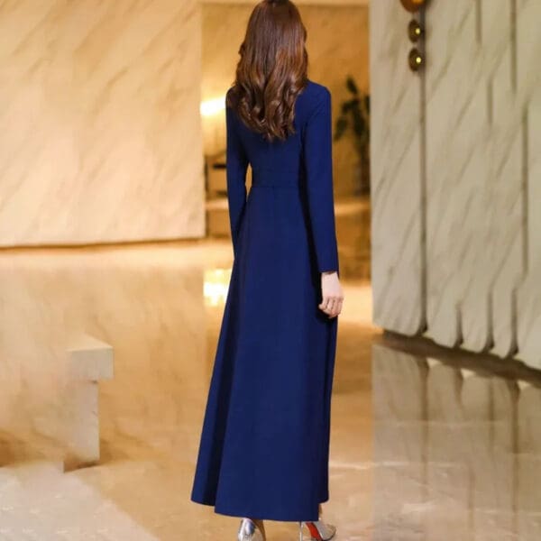 A woman in blue dress walking down hallway.