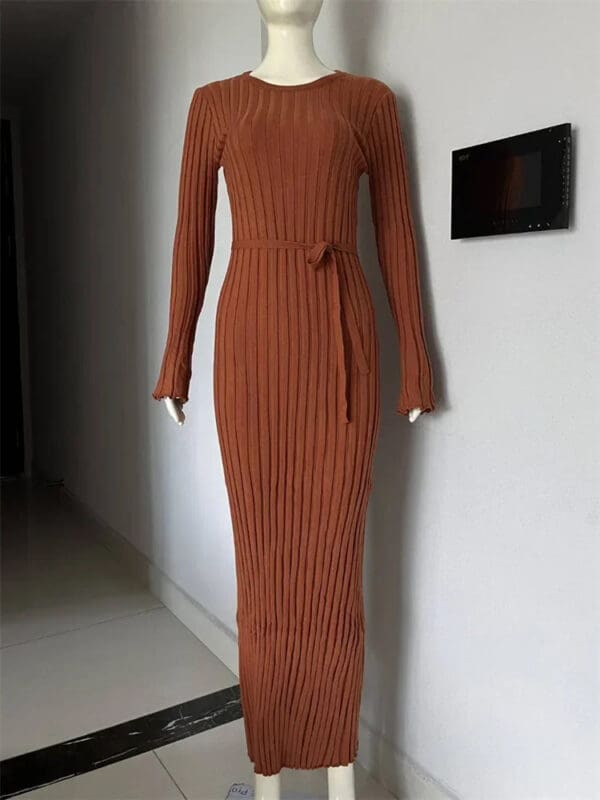 A long dress is shown on display in front of a wall.