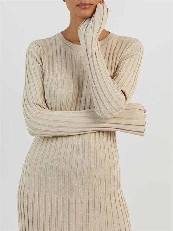 A woman in a beige sweater is posing for the camera.