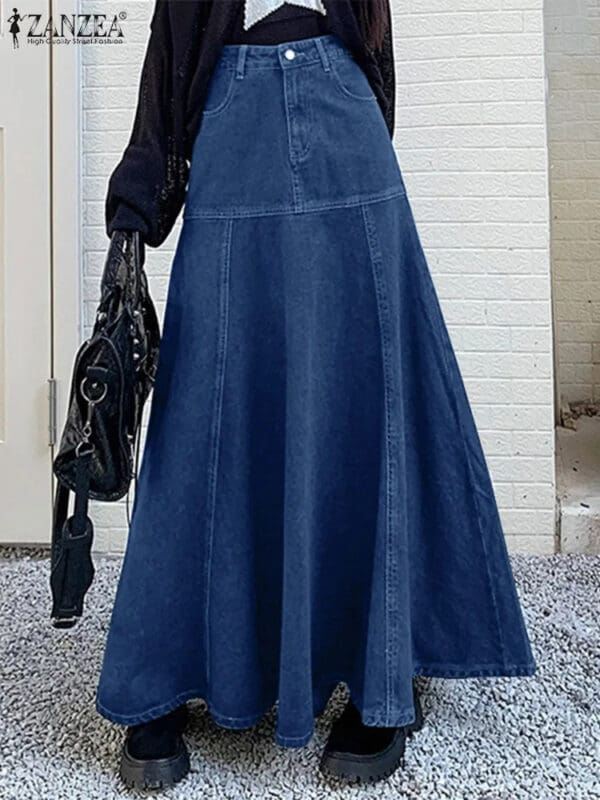 A woman in a long denim skirt holding onto a black purse.