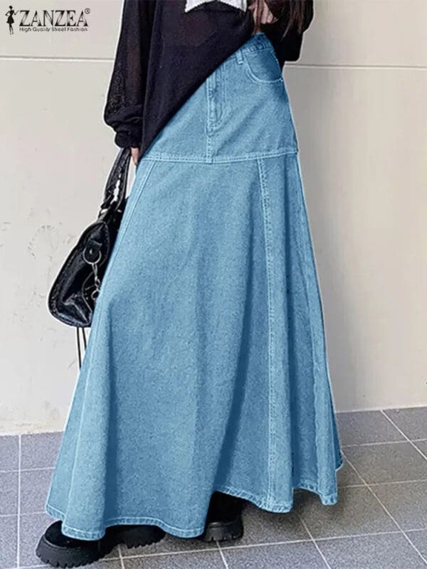 A woman wearing a long blue skirt and holding a purse.