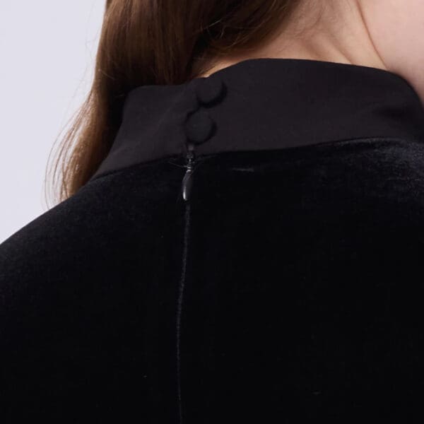 A woman wearing black jacket with buttons on the back.